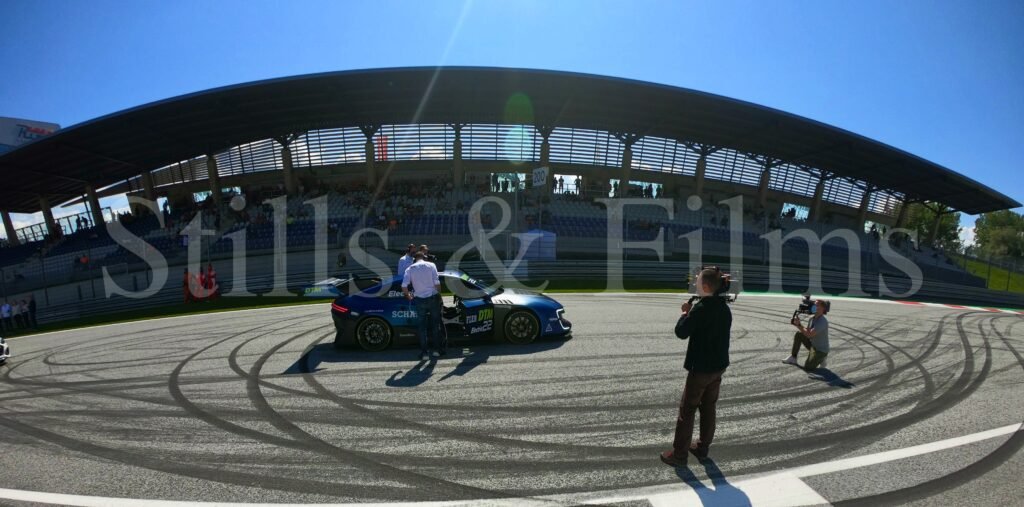 Automotive engineers around the high performance electric car checking on settings before a trial run. Our video crews filming the action.